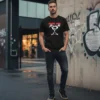 T-shirt preta de manga curta com estampa centralizada da banda Pearl Jam. A estampa exibe o nome 'Pearl Jam' em letras vermelhas acima do icónico desenho 'Stickman' em branco, com a palavra 'Alive' em letras pequenas vermelhas na base da figura.