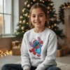Camisola de Natal branca infantil com estampa Stitch Disney Pai Natal e personalização Matilde. Criança a sorrir em frente a árvore de Natal.