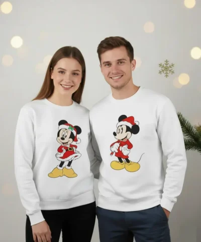 Casal a usar sweatshirts de Natal unissexo brancas com estampa festiva de personagem clássico com gorro de Pai Natal.