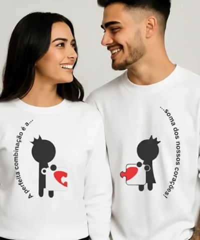 Casal a usar sweatshirts unissexo brancas com estampa de coração puzzle e frase “A Perfeita Combinação”.